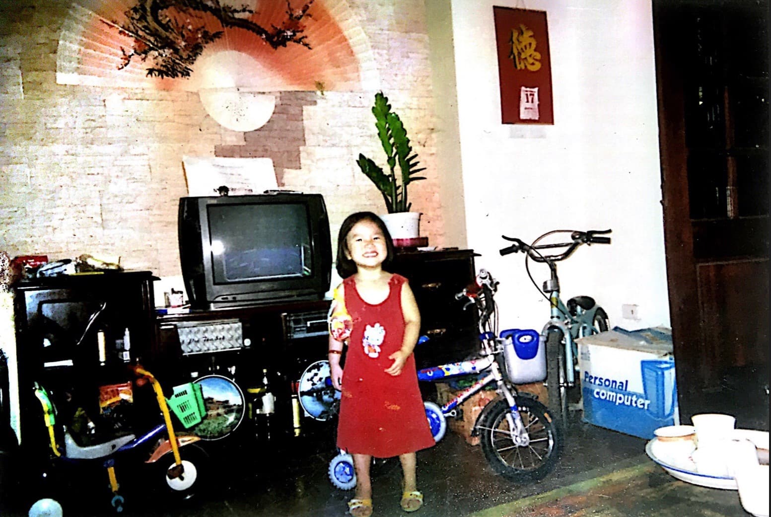 Child at home in Hanoi beside a Personal Computer box